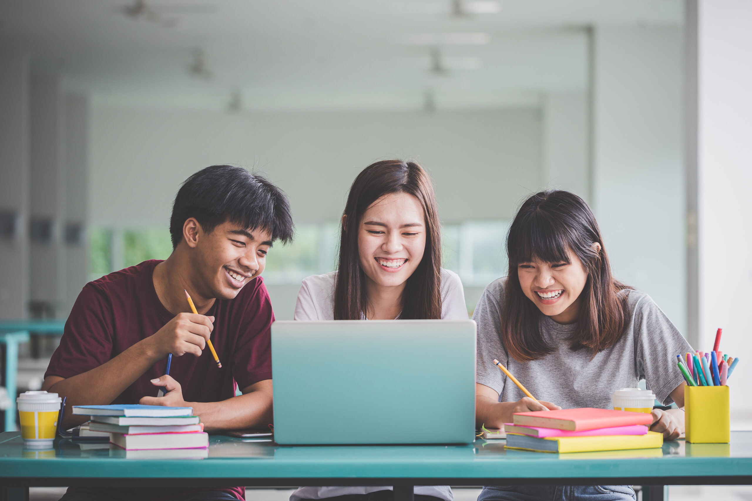 Group of friend or students smile happily with laptop on table